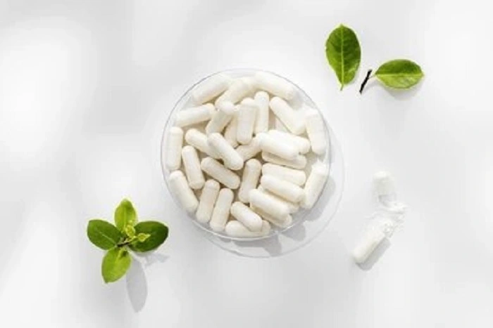 White Metatrim BHB capsules in a glass dish beside fresh leaves